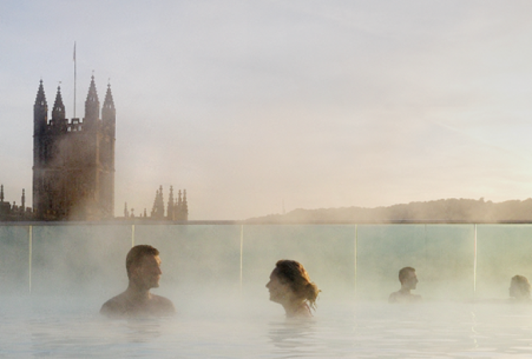 Couples in outdoor spa pool overlooking the city in Bath