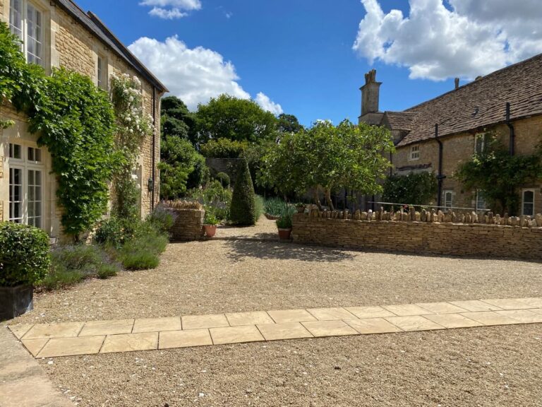 Outdoor paved area between two houses with trees and shrubs at Guyers House