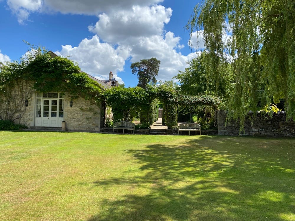 Gardens with stone outbuilding and leafy archways