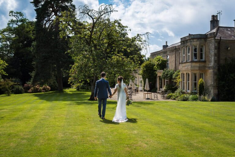 Happy couple in wedding attire on lawn in front of Guyers House Hotel